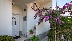 A house with a white exterior, a wooden staircase, and potted plants. - A1 - apt near beach with patio, parking and grill  (Stobreč)