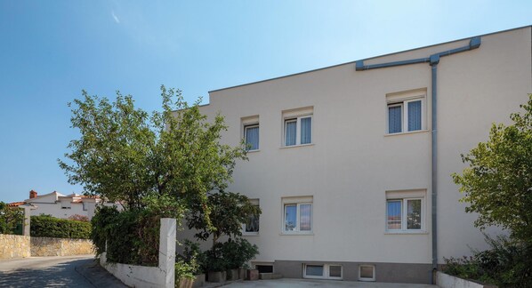 A building with multiple windows and a paved area in front. - A1 - apt near beach with patio, parking and grill  (Stobreč)