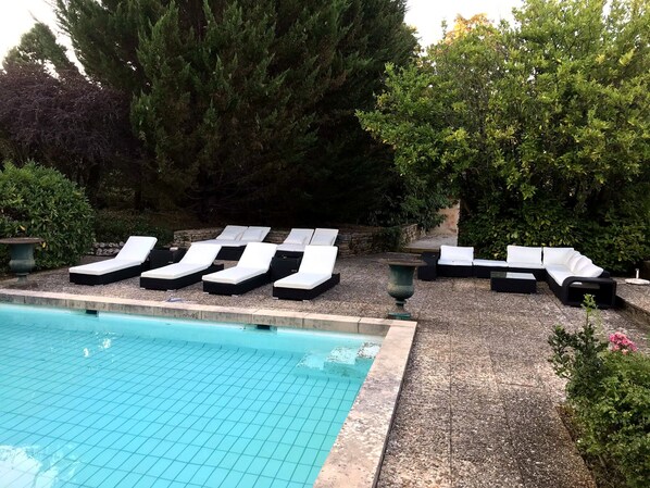 A poolside area with lounge chairs and a stone pathway.