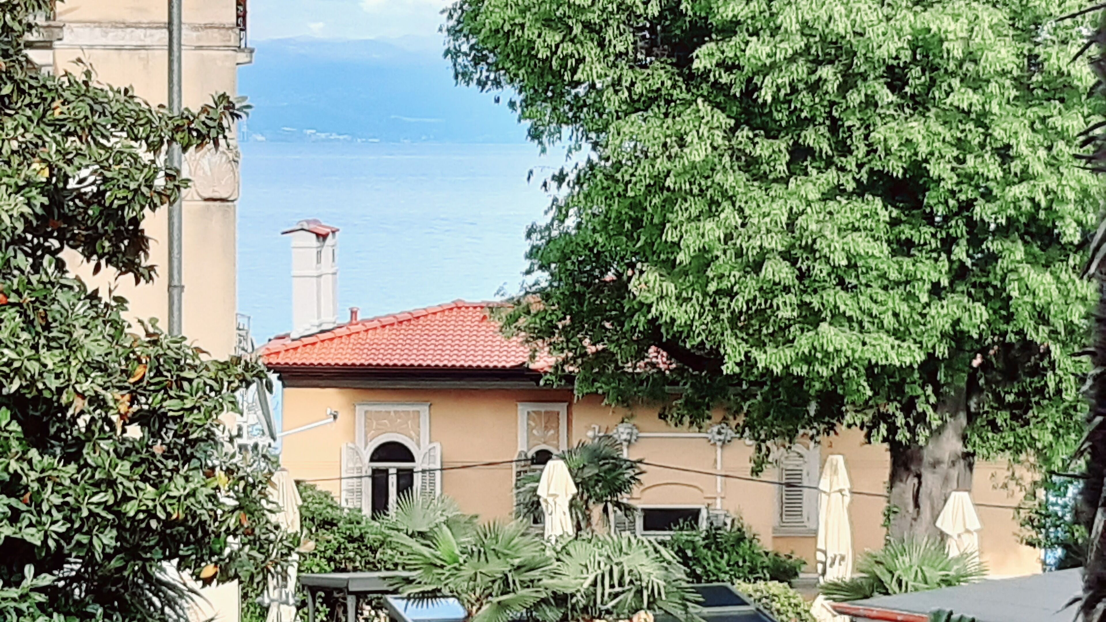 A building with a red-tiled roof, a small balcony, and a view of the sea.