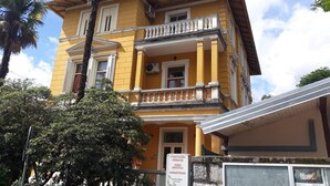 A two-story building with a yellow facade, a balcony with white balustrades, and a sign indicating a dental office. - 50m vom Meer entfernt (Lovran)
