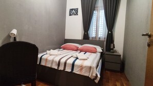 A bedroom with a bed, a desk, a chair, a nightstand, and a window with curtains. - 50m vom Meer entfernt (Lovran)