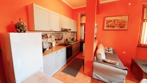 A compact kitchen with white cabinets, a refrigerator, and a dining area with a sofa and a small table. - 50m vom Meer entfernt (Lovran)