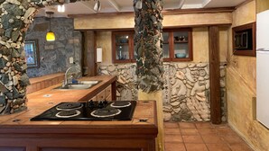 Uma cozinha com parede de pedra, armários de madeira, fogão e pia.