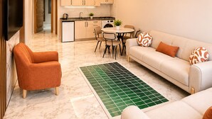 Una sala de estar moderna con sofá, sillón, mesa de comedor y zona de cocina.