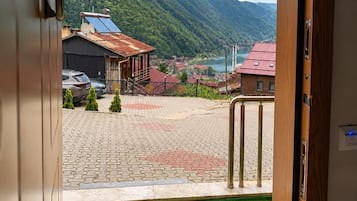 A hotel entrance with a view of a mountainous landscape and a paved area with a green lawn.