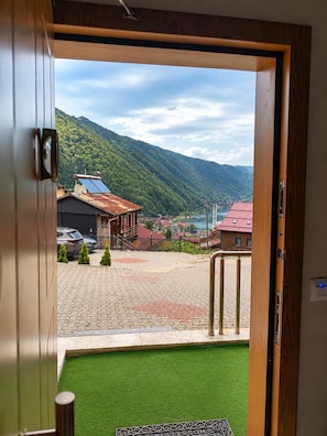 A hotel entrance with a view of a mountainous landscape and a paved area with a green lawn. - Auga Apart (Çaykara)