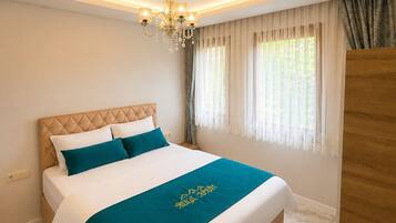 Un dormitorio con cama, candelabro, ventana con cortinas y armario de madera.