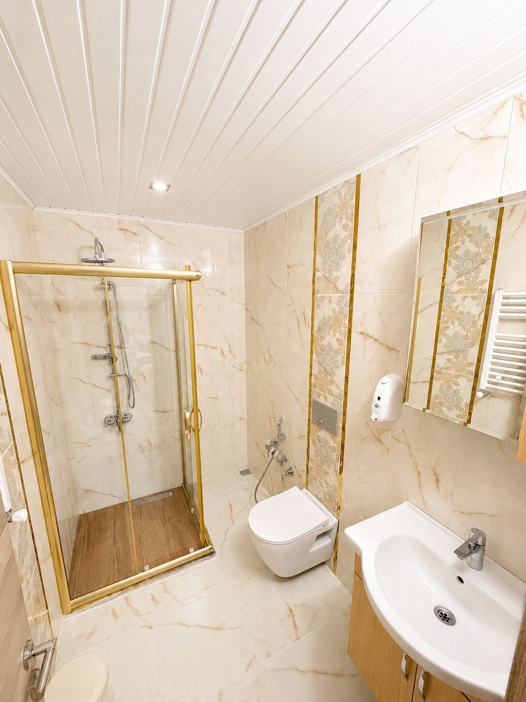 A modern bathroom with a glass-enclosed shower, a white toilet, and a sink with a marble countertop.