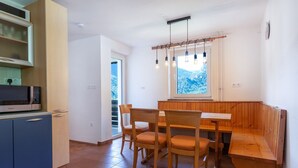 Uma cozinha compacta com micro-ondas, armários e uma área de refeições com cadeiras e um banco.