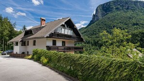 Uma casa em estilo chalé com telhado inclinado, varanda e vista para uma paisagem montanhosa.