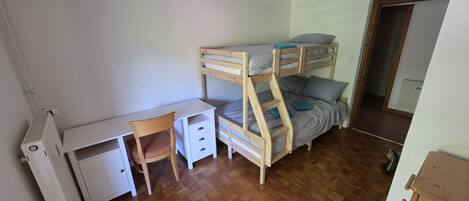 Una habitación con literas, un escritorio y una silla.