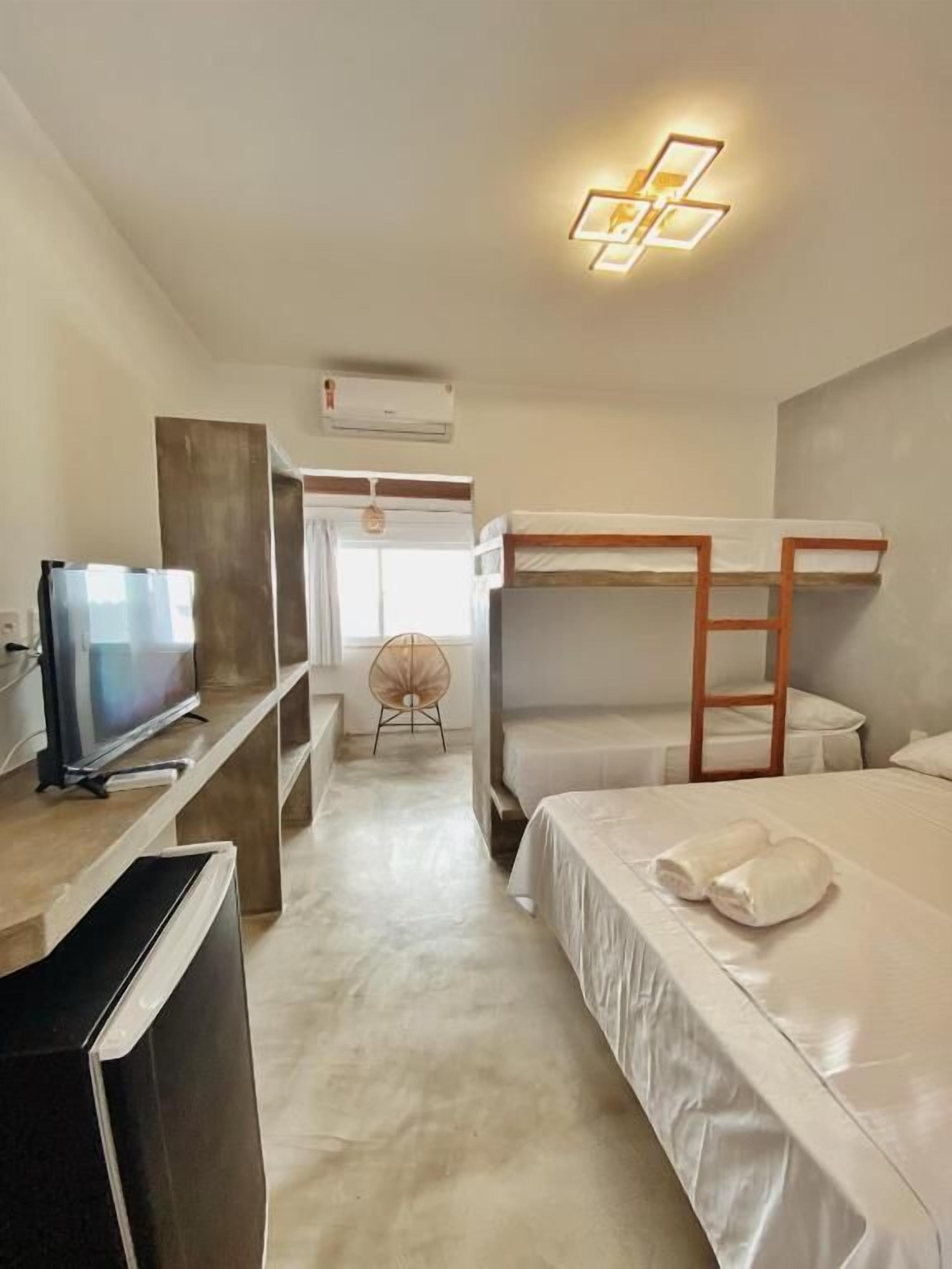 Une chambre d’hôtel avec des lits superposés, une télévision, un bureau et une chaise.