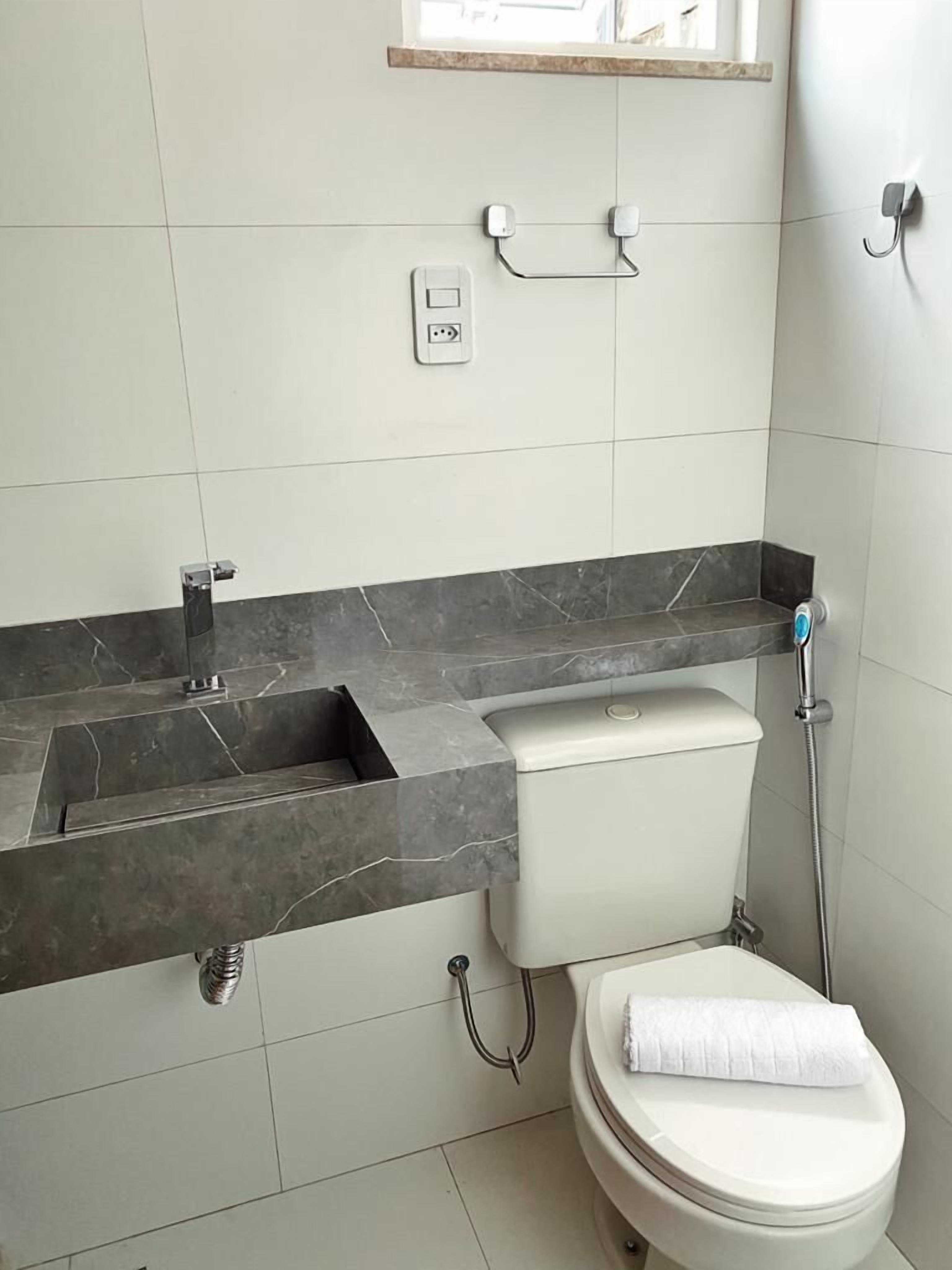 A bathroom with a marble countertop, a toilet, and a shower.