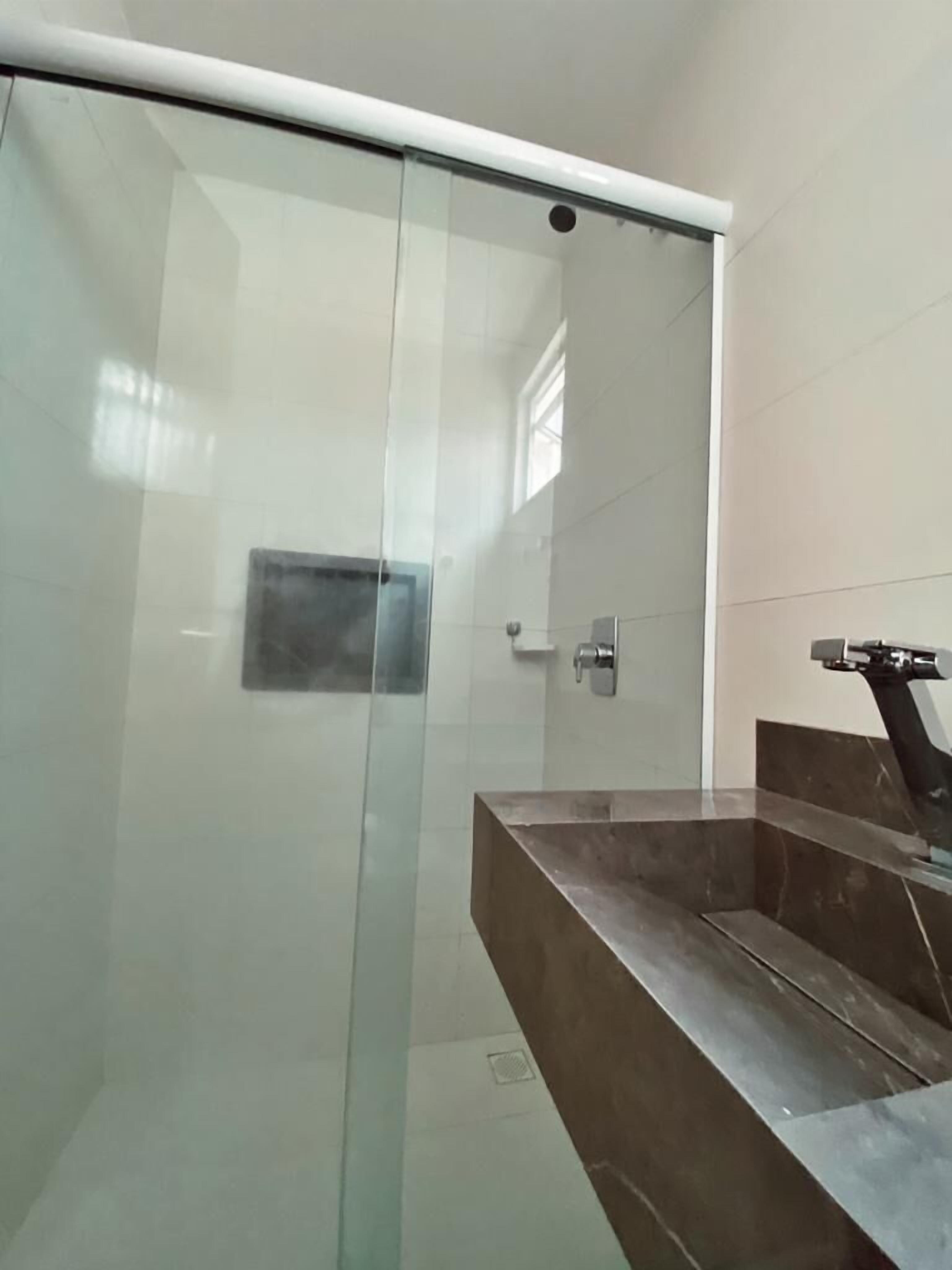 Une salle de bain moderne avec une douche à parois de verre, un lavabo en marbre et un robinet mural.