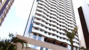 A tall, modern building with a unique zigzag facade, multiple balconies, and a clear sky in the background. - Astron Suítes Mondial Salvador by Nobile (Salvador)