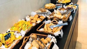 A buffet with various baked goods and a vase of yellow flowers. - Astron Suítes Mondial Salvador by Nobile (Salvador)
