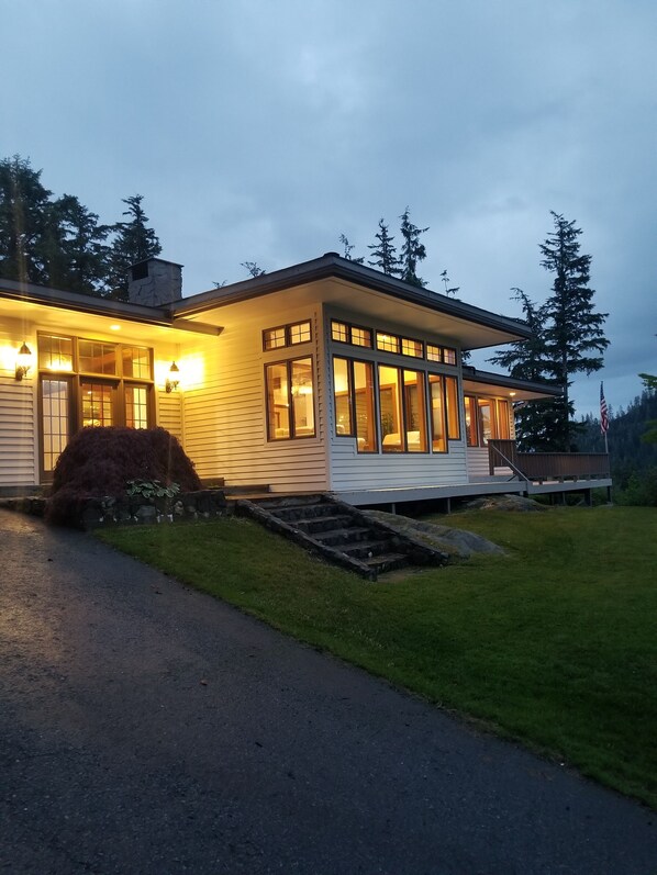 Ein zweistöckiges Haus mit Veranda, großen Fenstern und einem Steinkamin.