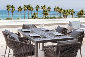 A dining table set for four with a view of the ocean and palm trees. - ApartUP Denia Beachfront Deluxe (Denia)