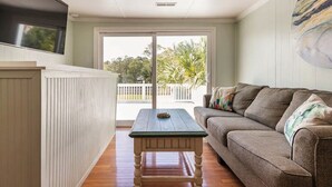 A living room with a wooden table, a sofa, and a view of the outdoors.