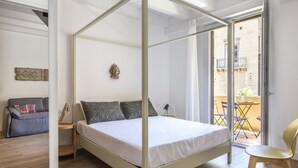 A bedroom with a four-poster bed, a sofa, a chair, and a small table. - Le Niche Holiday Home - Balcony by Wonderful Italy (Palermo)