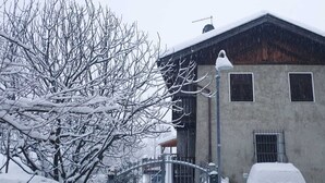 A snow-covered building with a metal fence and a street lamp.
