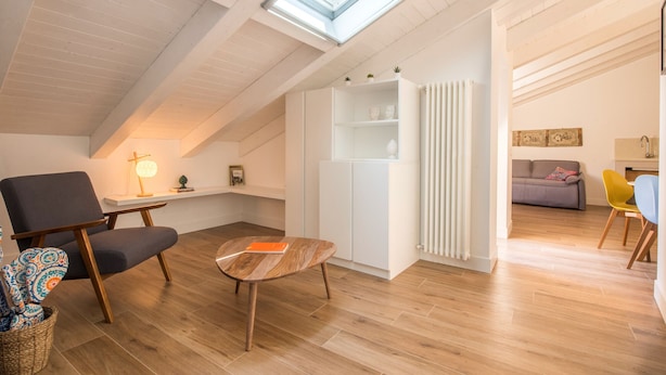 A modern loft apartment with a sloped ceiling, skylights, a built-in white cabinet, a wooden coffee table, a gray sofa, and a yellow chair. - Le Niche Holiday Home - Terrace by Wonderful Italy (Palermo)