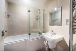 A modern bathroom with a glass-enclosed shower, a white sink, and a mirror above the sink. - 1-Bed Fitzrovia Flat · Balcony & Views · Sleeps 3 (London)