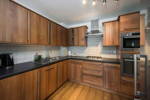 A modern kitchen with wooden cabinets, stainless steel appliances, and a black countertop.