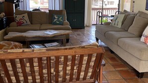 A living room with a sofa, a wooden coffee table, and a ceiling fan. - North Padre Island waterfront canal  home w/private dock and pool (Corpus Christi)