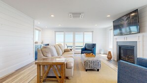 Un salon avec un canapé, un pouf et une cheminée.