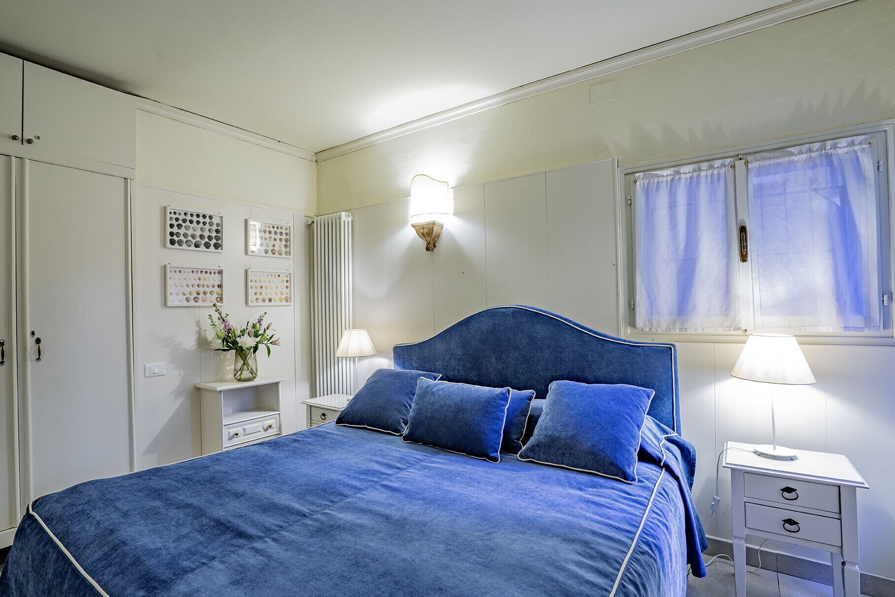 A bedroom with a large bed, bedside tables, a dresser, and a window with curtains.