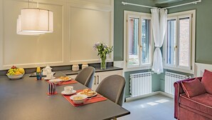 A dining area with a table set for breakfast, a radiator, and a window with curtains. - Lo Squero 2 Charming Apartment in Dorsoduro (Venice)