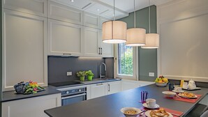 A modern kitchen with white cabinets, a central island with breakfast items, and pendant lights. - Lo Squero 2 Charming Apartment in Dorsoduro (Venice)