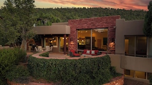 A modern house with a patio, outdoor seating, and a view of the surrounding forest.