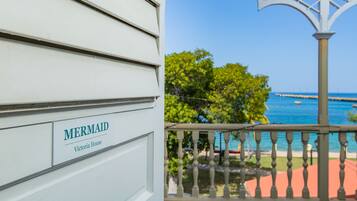 Un bâtiment blanc avec une enseigne indiquant « MERMAID Victoria House » et un balcon offrant une vue sur la mer et un quai.