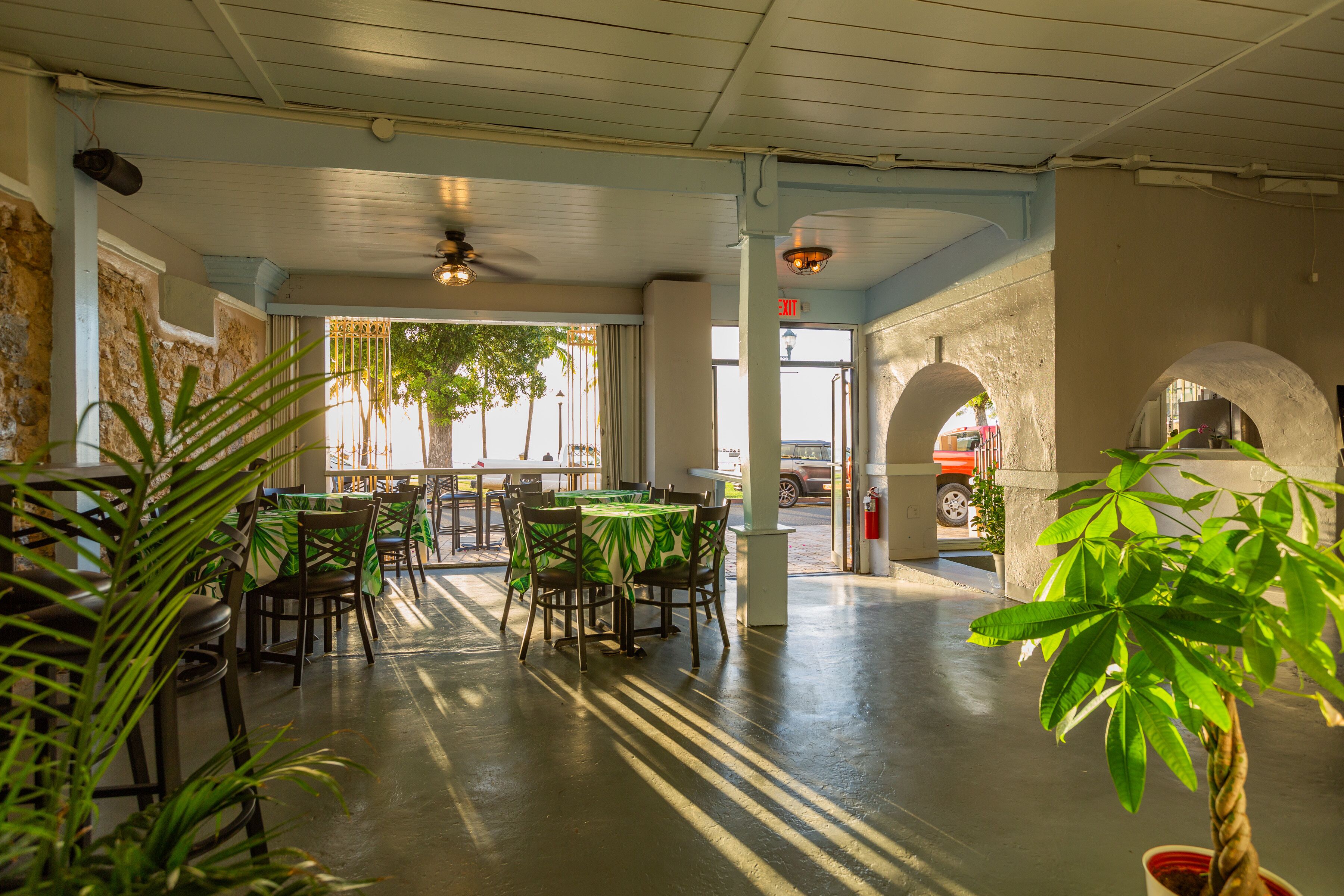 An indoor dining area with tables and chairs, a ceiling fan, and a view of the street outside.
