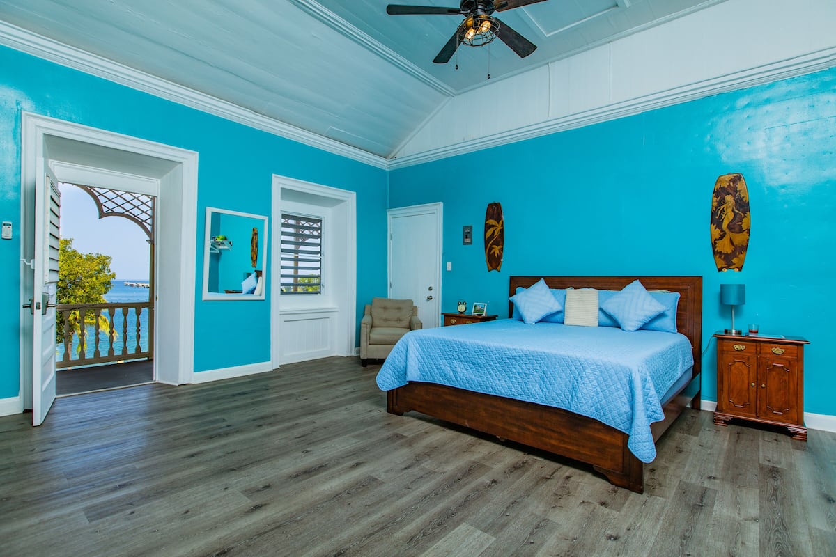 A bedroom with a wooden bed, a view through an open door, a ceiling fan, and a wooden cabinet.