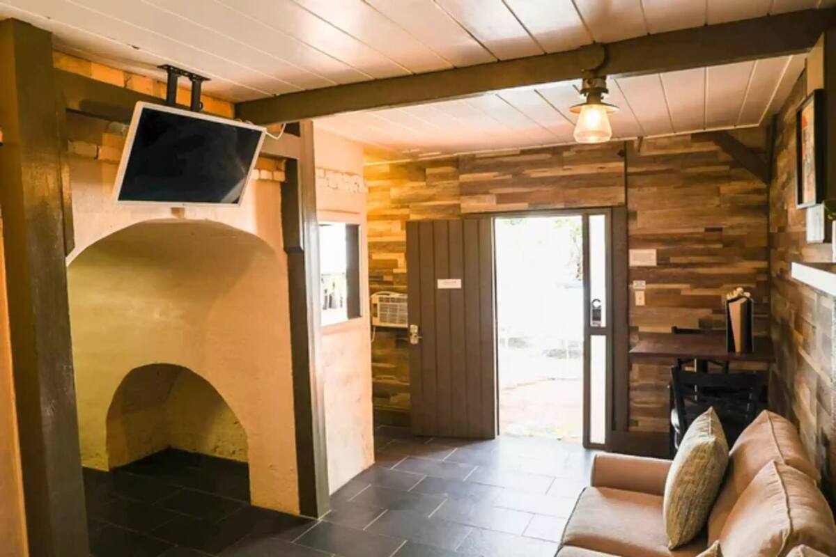 A cozy interior with a stone fireplace, a flat-screen TV mounted on a wall, and a wooden ceiling.