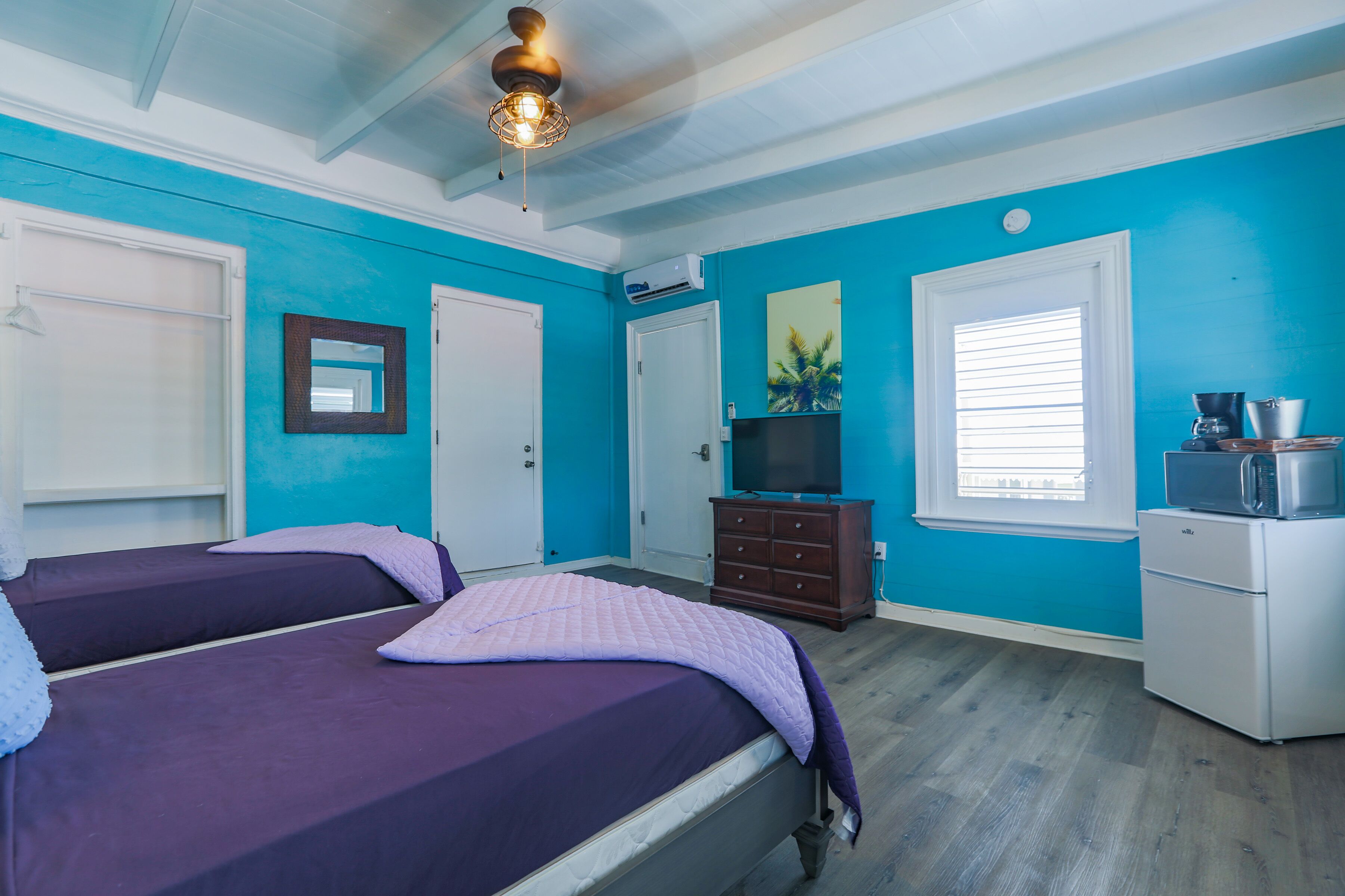 A room with two beds, a dresser, a TV, and a microwave.