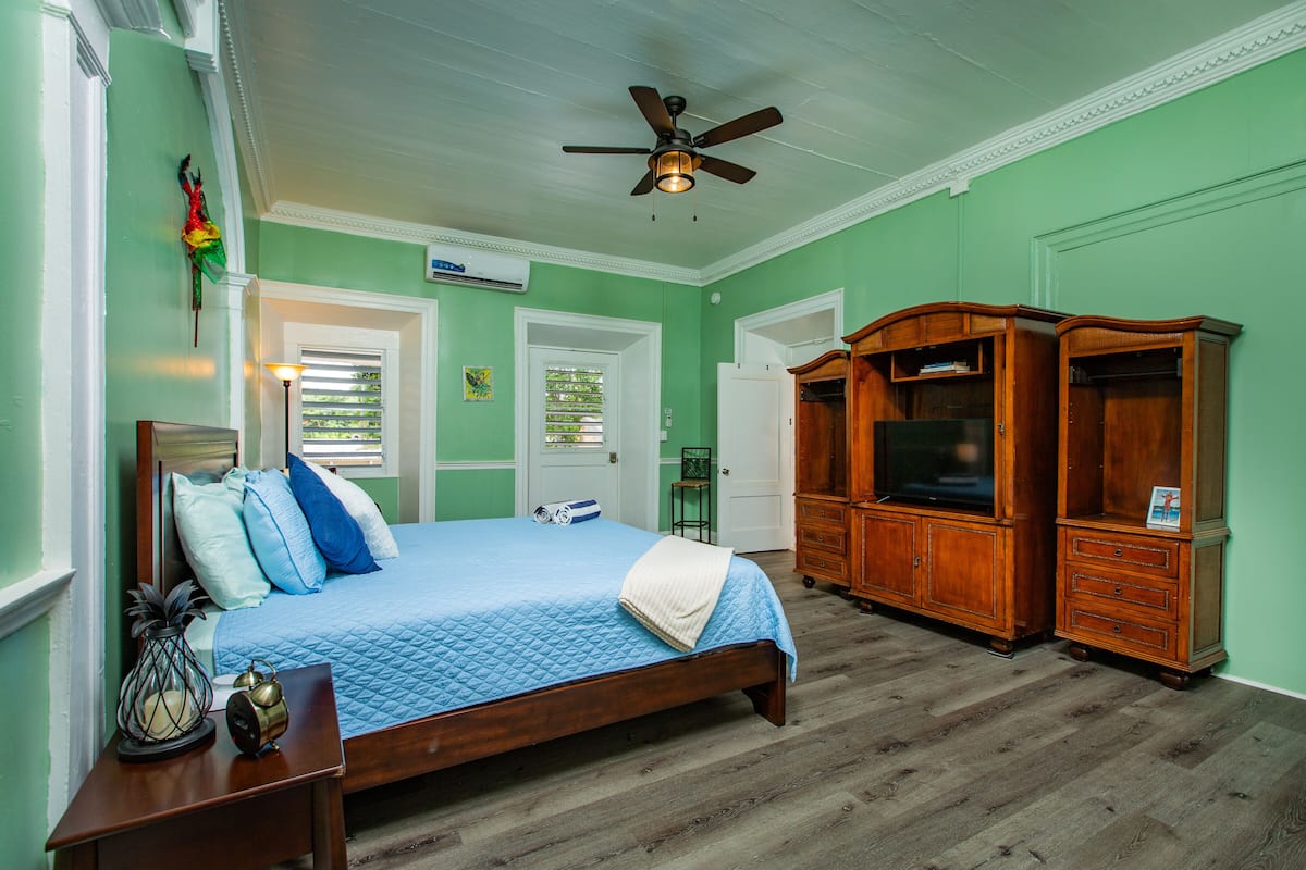 A bedroom with a bed, wooden wardrobe, and a ceiling fan.