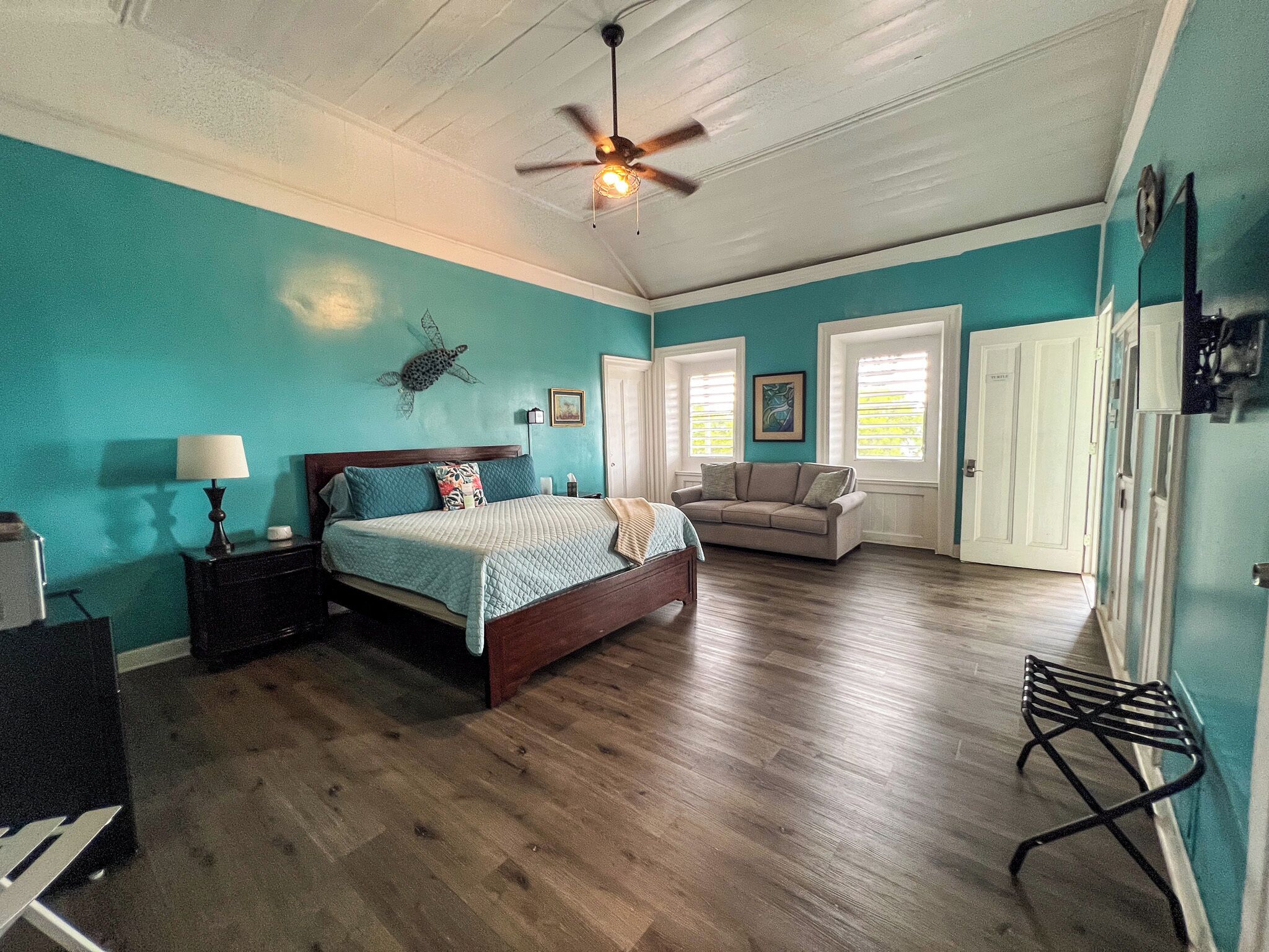 A bedroom with a bed, a nightstand, a dresser, a ceiling fan, and a window with blinds.