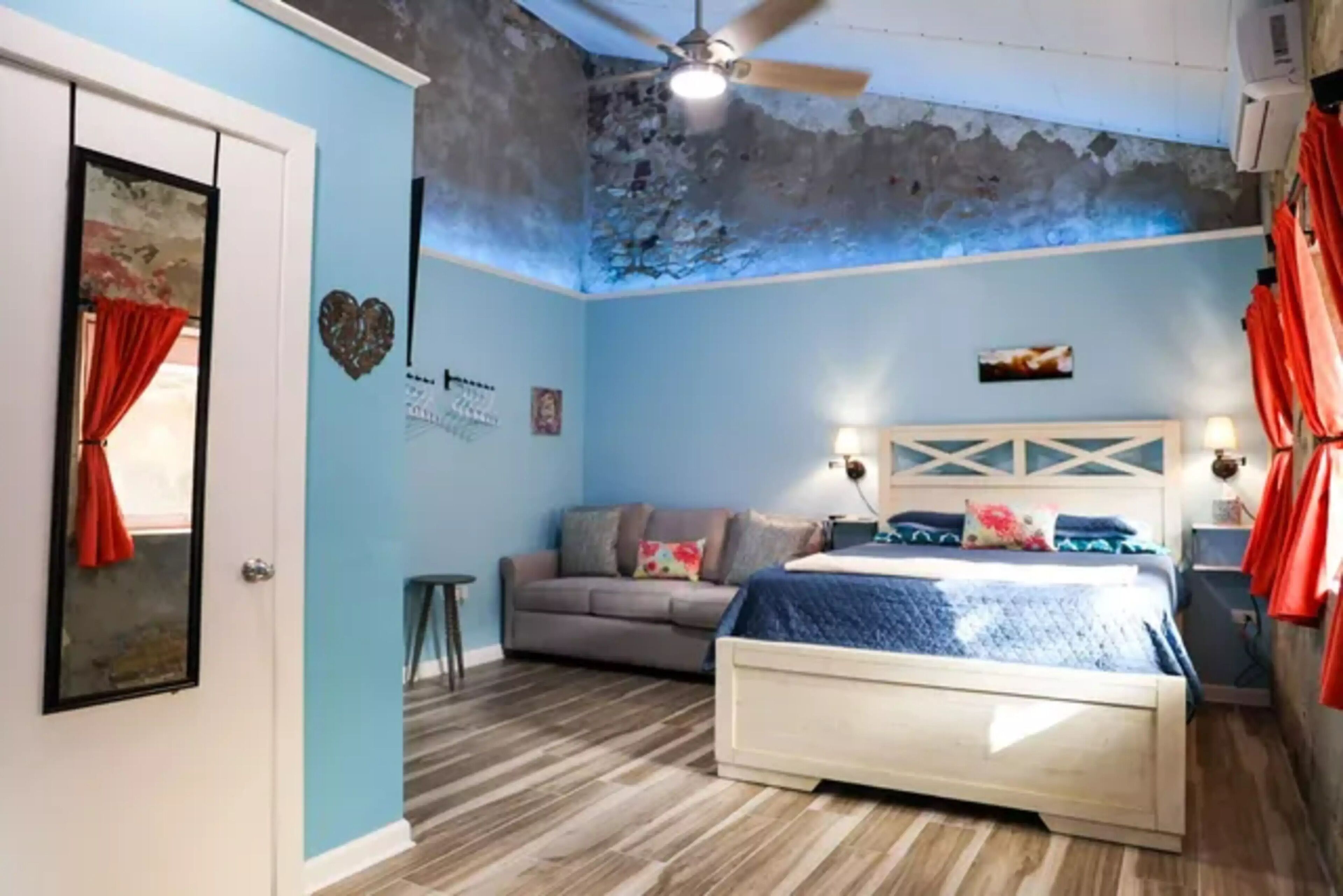 A bedroom with a bed, a sofa, and a ceiling fan.