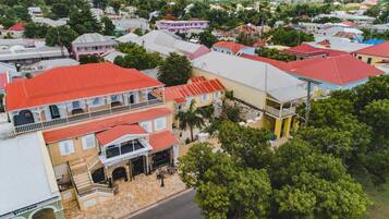 Vista aérea de una zona residencial con casas coloridas, un edificio de dos pisos destacado con balcón, y una calle con acera.