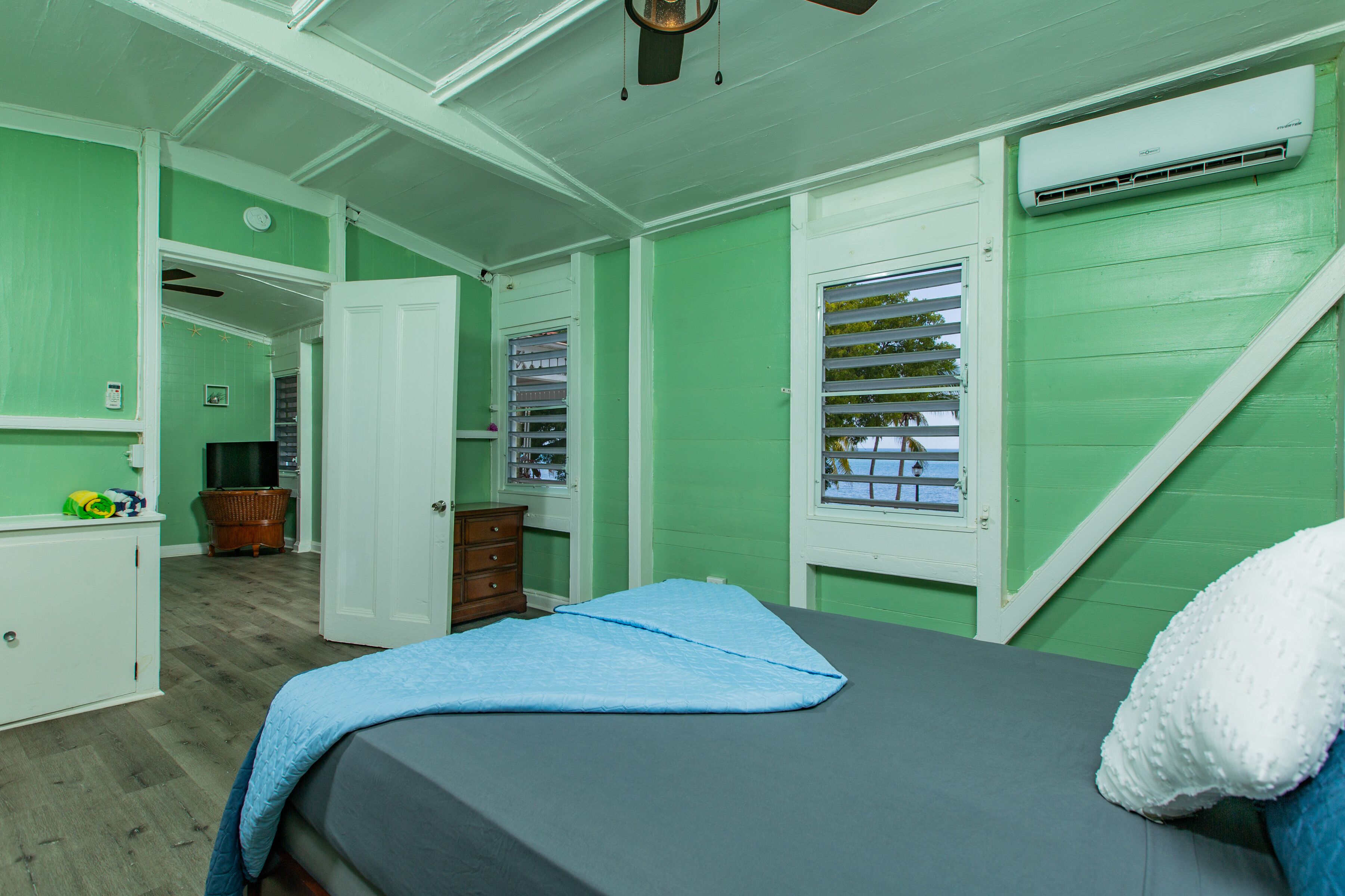 Quarto com cama, penteadeira e janela com persianas.