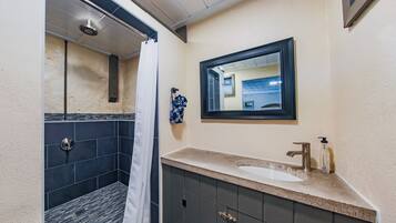 Une salle de bain avec une douche, un lavabo et un miroir.