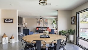 Un espace repas moderne avec une table ronde en bois, des chaises noires et un ventilateur de plafond.