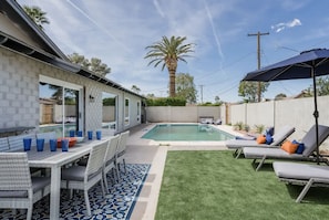 A backyard with a swimming pool, a dining area with outdoor furniture, and a covered patio area. - Colorful Desert Hideaway: Heated Pool & Hot Tub (Scottsdale)