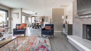 Un salon spacieux avec deux fauteuils aux couleurs sombres, un tapis à motifs et une cheminée.