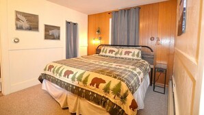 Un dormitorio con una cama, una mesita de noche, una lámpara y dos cuadros colgados en la pared.